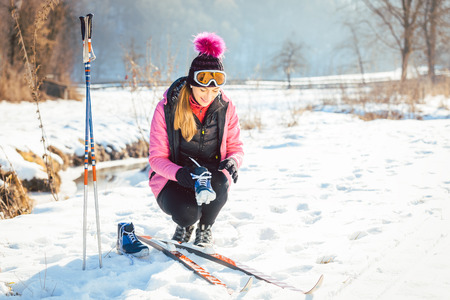 Woman cross country skier putting on ski on the slopeの写真素材