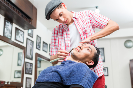 Close-up of man shaving in barbershop with straight razorの写真素材