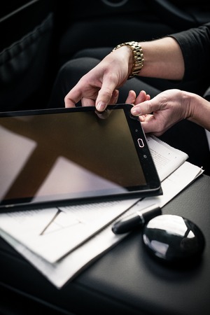 Close-up of businesswomans hand taking digital tablet in car