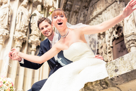 Close-up of excited married couple posing in front of ancient churchの写真素材