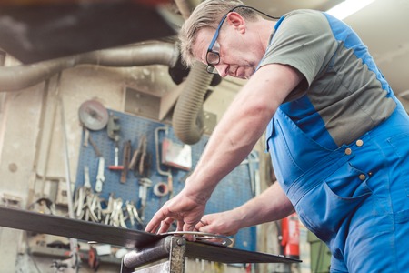 Metalworker man in his workshop working on project measuring and planning