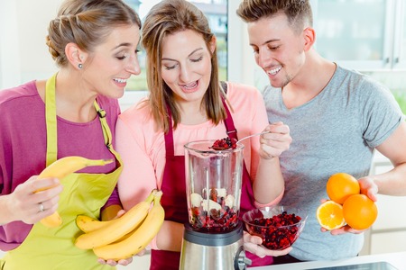 Two women preparing fruit juice in the blenderの写真素材