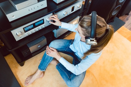 Woman with headphones listening to music via the Hi-Fi stereo in her homeの写真素材