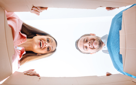 Woman and man moving into new apartment unpacking the moving boxesの写真素材