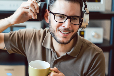 Man drinking coffee and listening to music being carried away by the soundの写真素材