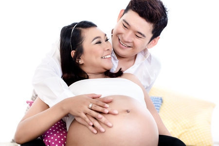 Close-up of pregnant woman leaning on her husbands shoulder looking at each otherの写真素材