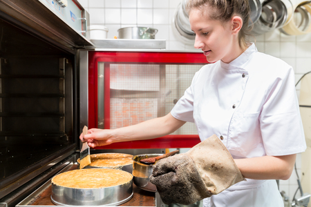 Pastry baker putting pies or cakes in oven to bakeの写真素材