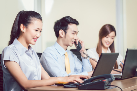 Happy group of businesspeople working in the office with laptop and telephoneの写真素材
