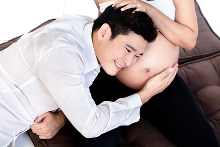 Overhead view of a man listening to his pregnant wifes tummyの写真素材