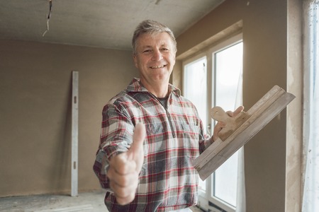 Friendly plasterer giving thumbs-up in the interior of newly constructed houseの写真素材