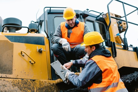 Worker sitting on heavy excavation machinery in mining operation