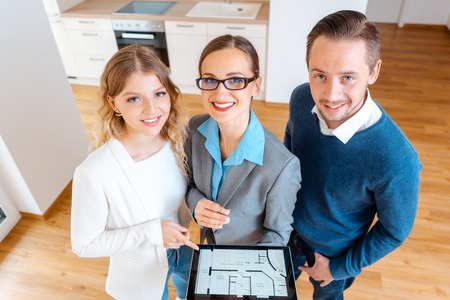 House broker and clients as a couple in new apartment looking into cameraの写真素材