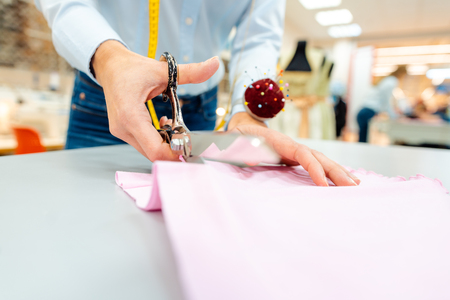 Tailor cutting fabric with scissors, close-upの写真素材