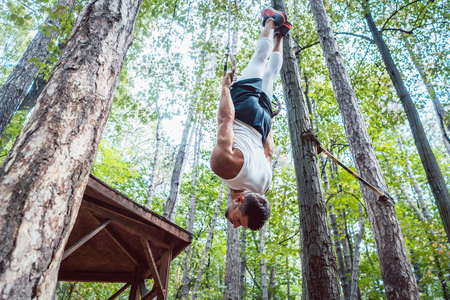 Strong and handsome man exercising for better fitness on rings in outdoor gym
