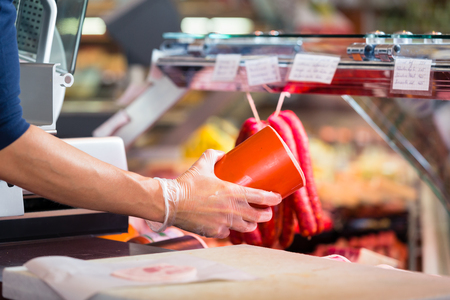 Woman in butcher shop holding sausage in her hands to sell themの写真素材