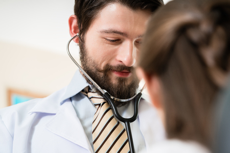 Smiling doctor checking female patientの写真素材