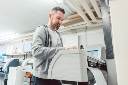 Man preparing large format printer for a banner print job on vinyl