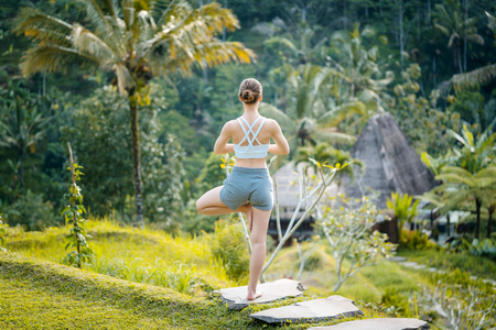 Woman on rice paddy in yoga pose relaxing in her vacationの写真素材