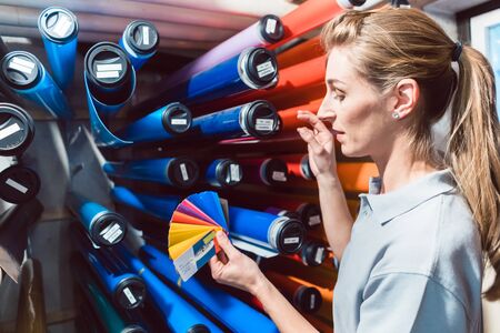 Woman in advertising material production looking for the right film color checking it with fan