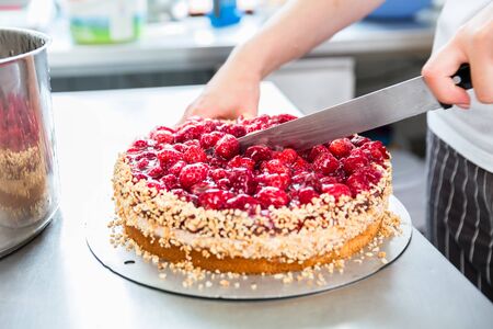 Close-up of woman confectioner or patissier cutting raspberry pie