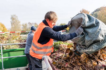 Man giving waste green in container on recycling center outdoorsの写真素材