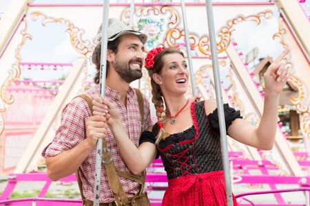 Woman and man enjoying a swing on the Oktoberfest or Bavarian fairの写真素材