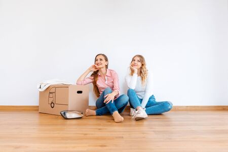 Two women in empty new apartment dreaming of how to decorate it