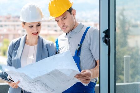 Principal and builder reading blueprints or building plans on construction siteの写真素材
