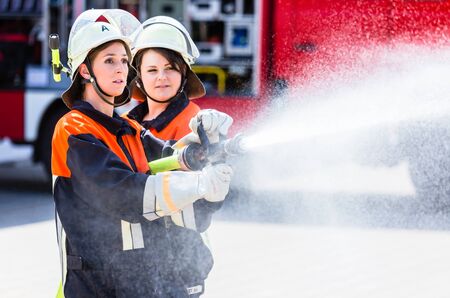 Female fire fighters spouting water to extinguish fireの写真素材