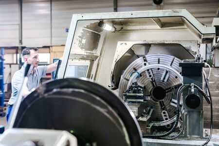 Worker man operating a CNC lathe in factoryの写真素材
