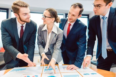 Team analyzing financial data in charts on a table discussing their findingsの写真素材