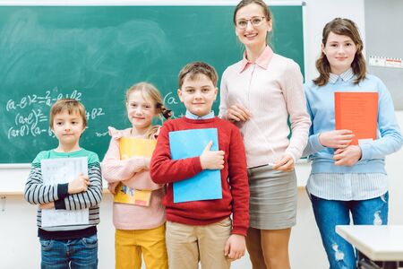 Proud students with books and teacher standing in school classの写真素材