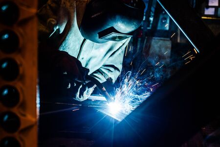 Welder working in factory with lots of sparks flying