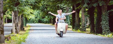 Happy young couple enjoying on old-fashioned scooterの写真素材
