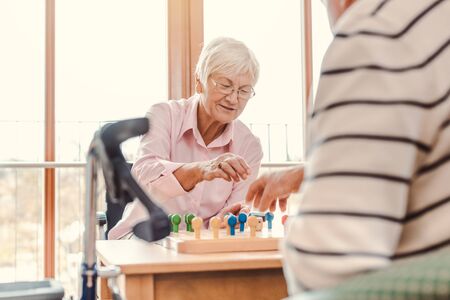 Two seniors, man and woman, in a nursing home playing a board gameの写真素材