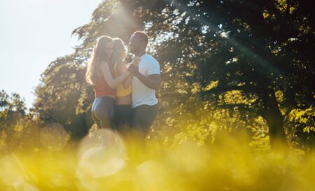 Three friends having fun dancing kizomba on a meadow in afternoonの写真素材