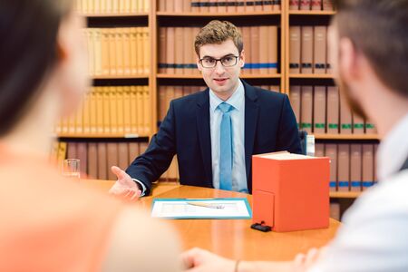 Notary advising couple on marriage settlement in his officeの写真素材