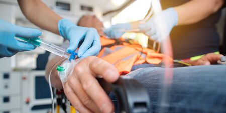 Emergency doctor administering injection needle in ambulance, closeup shotの写真素材