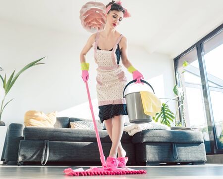Housewife going at the spring clean holding bucket and broomの写真素材