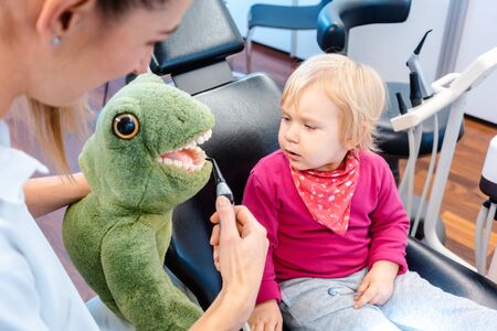 Little child in dentists surgery learning how to brush teeth with giant toothbrush