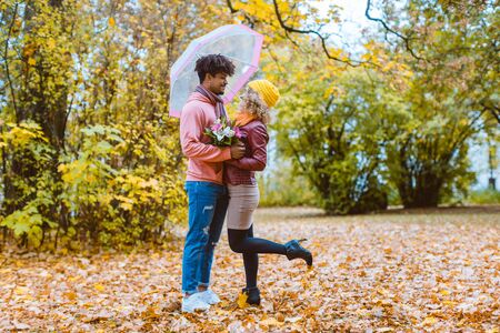 Man and woman of different ethnicity hugging in fall during a walk