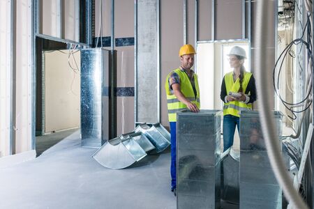 Construction workers inspecting parts of ventilation shafts to be installed in a building