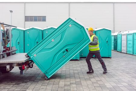 Rental lavatory being loaded on truck by worker