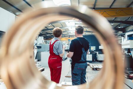 Workers standing on the factory floor seen through a ring workpiece