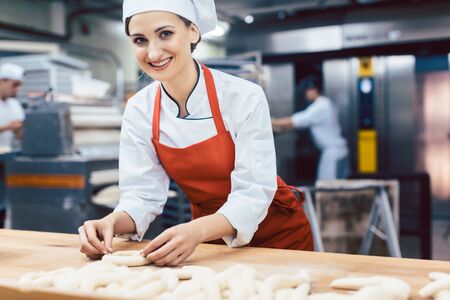 Baker woman forming pretzels and bread, medium shot