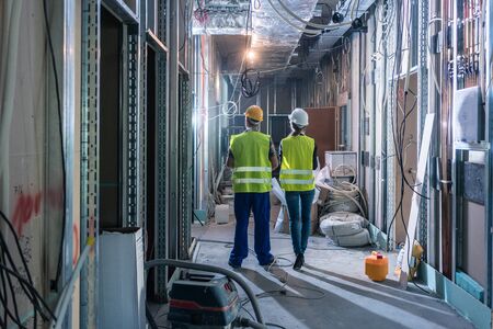 Builder and construction worker inspecting the site to plan further