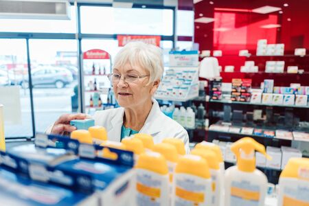Experienced saleslady in drug store sorting thru her goods in the shelvesの写真素材