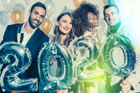Party people women and men celebrating new years eve 2020 with sparklers and Champagne