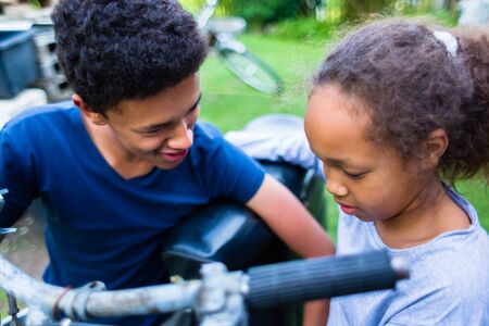Smiling boy and girl looking at motorcycle in the park