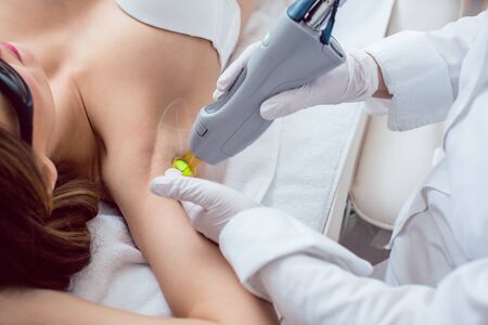Woman during hair removal in the armpit region using modern laser technologyの写真素材